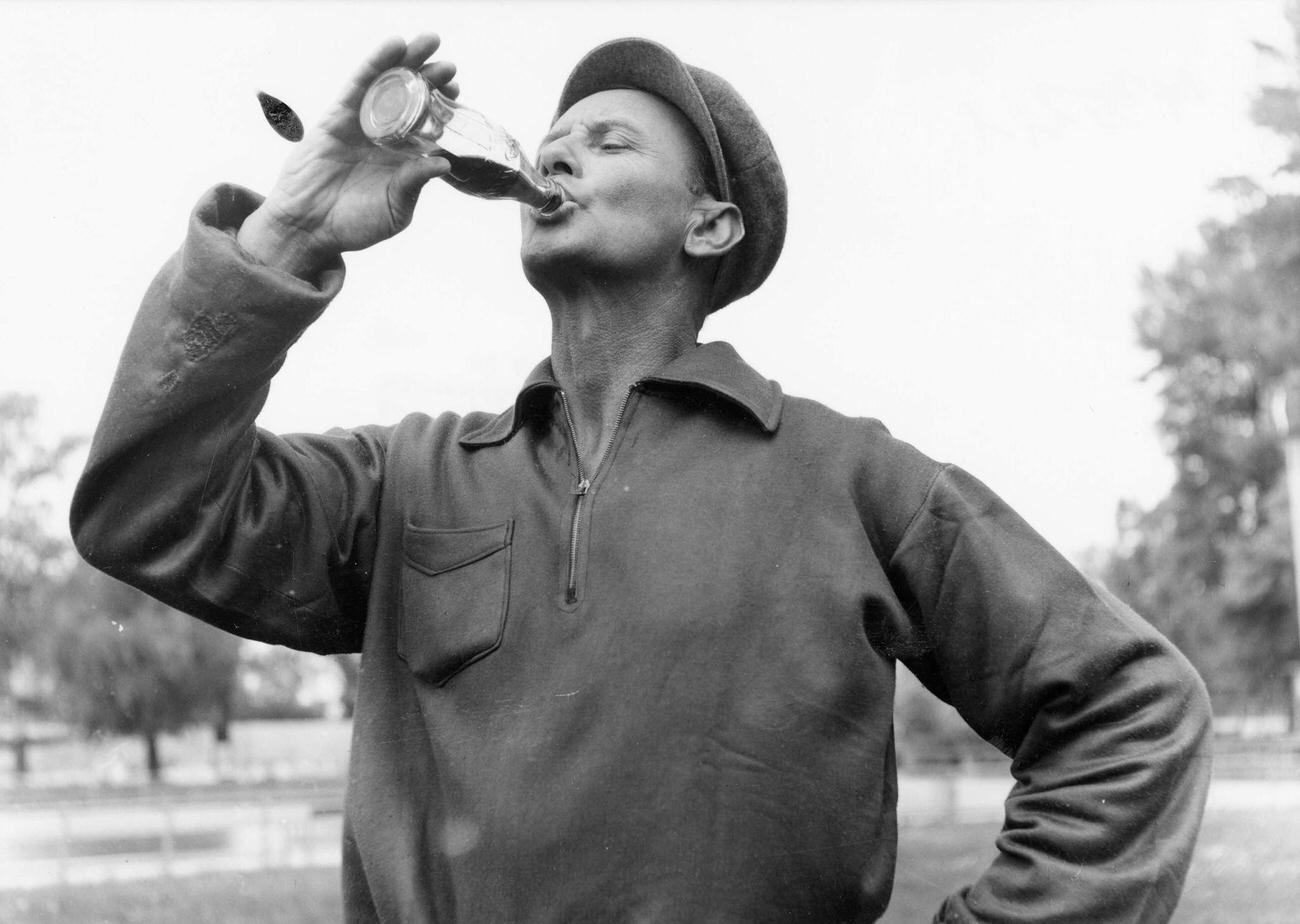 A man drinking from a Coca-Cola bottle, 1955.