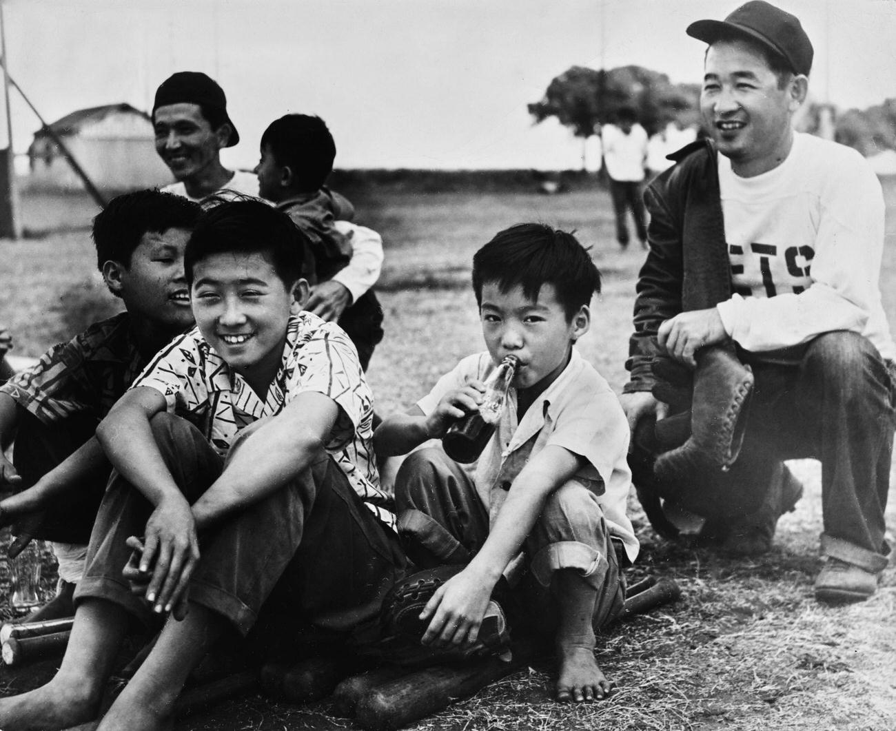 Young Hawaiians, one drinking Coca-Cola, waiting to bat during a baseball game in Hawaii, circa 1955.