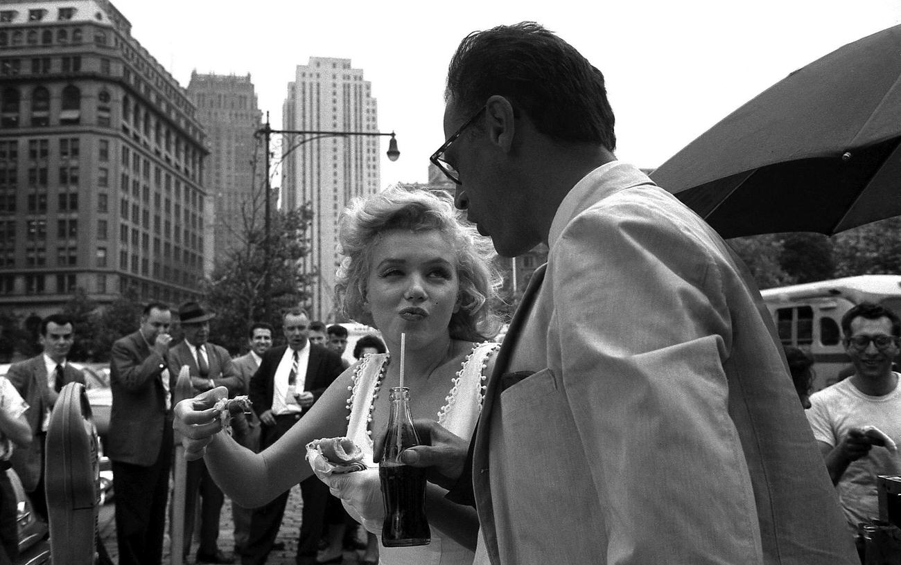 Marilyn Monroe eating a hot dog with husband Arthur Miller in New York, 1957.