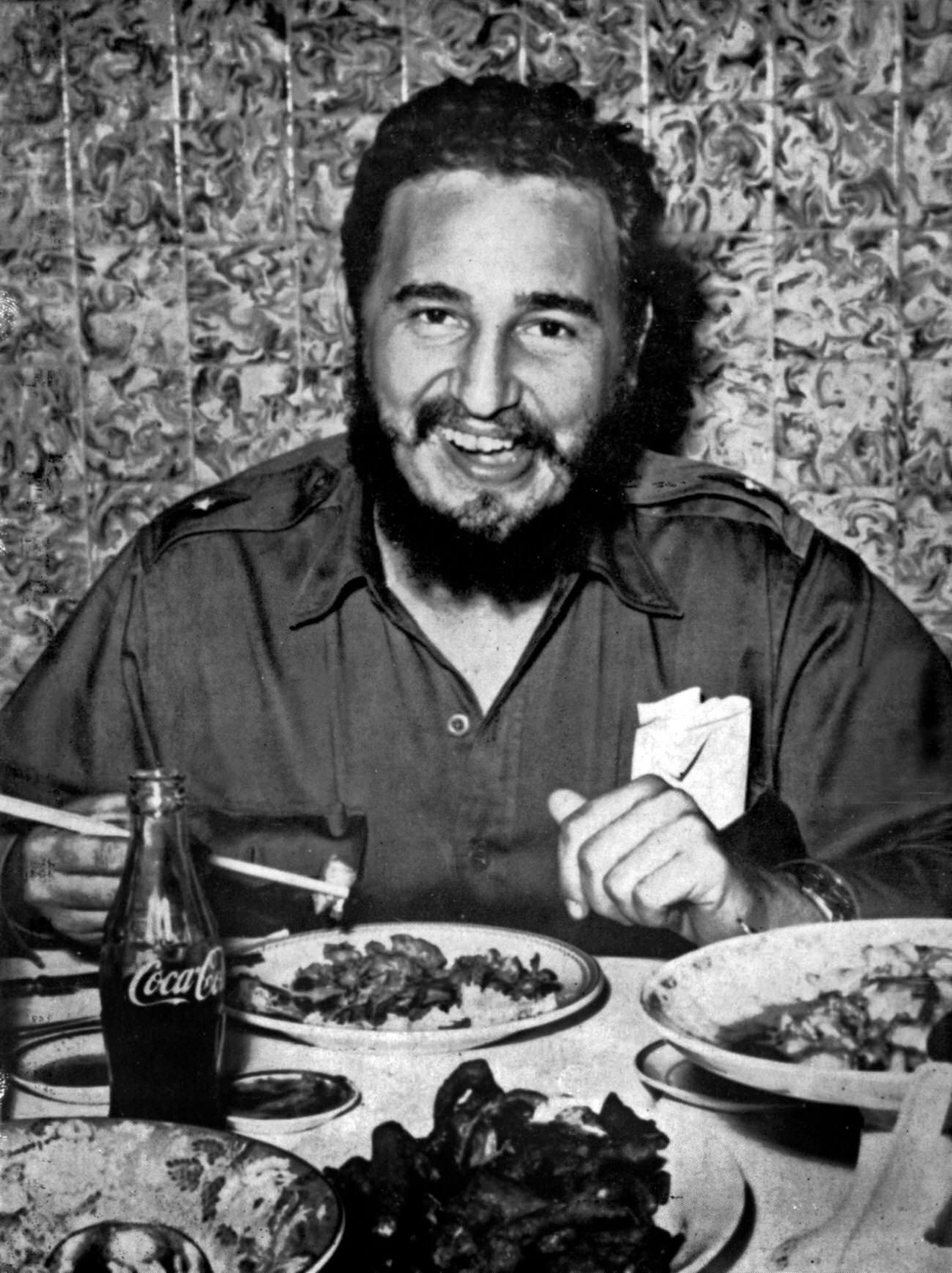 Fidel Castro eating a Chinese meal with chopsticks and drinking Coca-Cola, circa 1960.