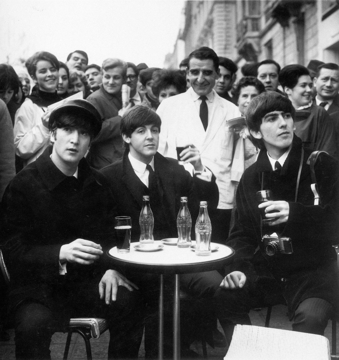 Beatles John, Paul, and George enjoying Coca-Cola at a cafe in Paris1964.