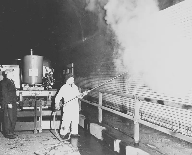 Workmen cleaning soot off bricks, "Jenny" cleaning machine and Ford truck in background.