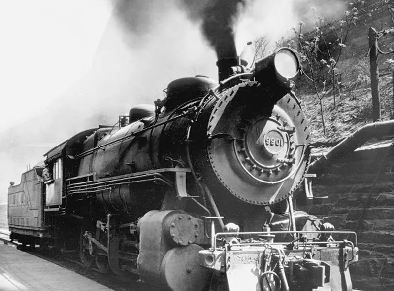 Steam locomotive #9901 expelling smoke at a railway station.