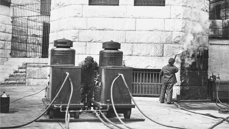 Man cleaning Allegheny County Courthouse exterior, another smoking near a cleaning machine.