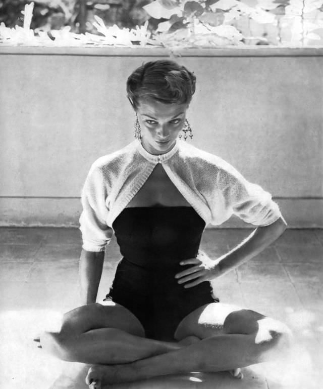 Jean Patchett in a strapless navy-blue wool suit with back buttons and a brief white wool sweater by Tina Leser, in Jamaica, 1949.