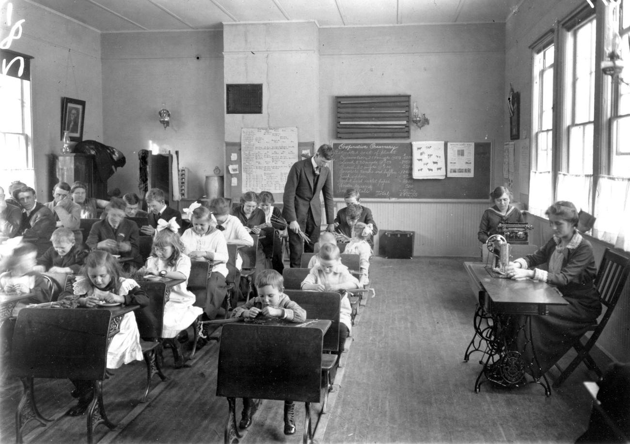 Students learning in a one-room schoolhouse, Wisconsin, early 1900s, including sewing and typing.