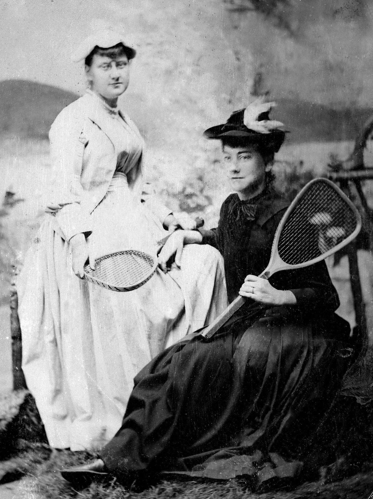 Two women posing with tennis racquets, circa 1890.