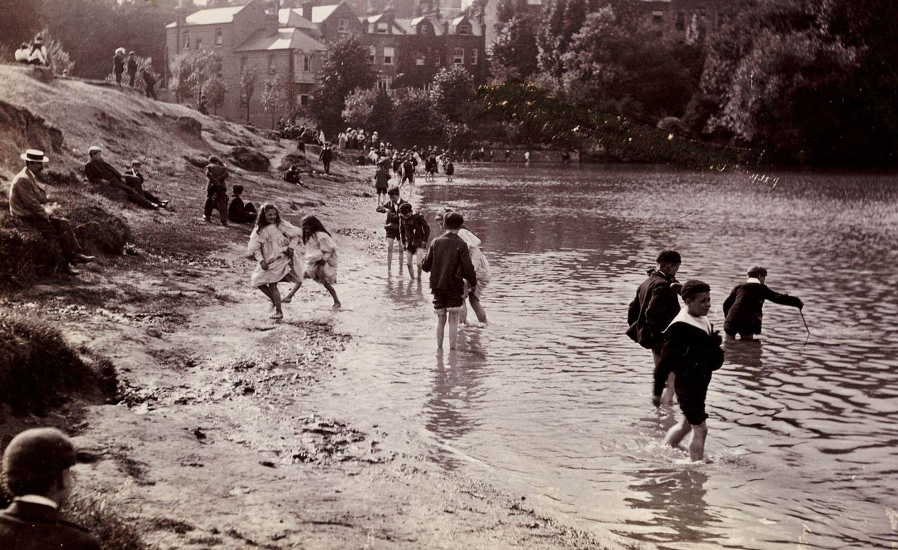 Children playing in a river on a summer day, circa 1900.