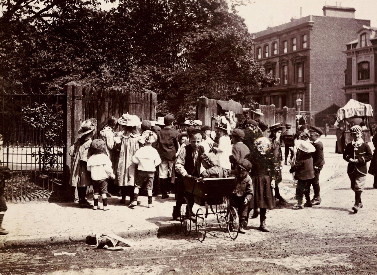 Children gathering near a park entrance, circa 1900.