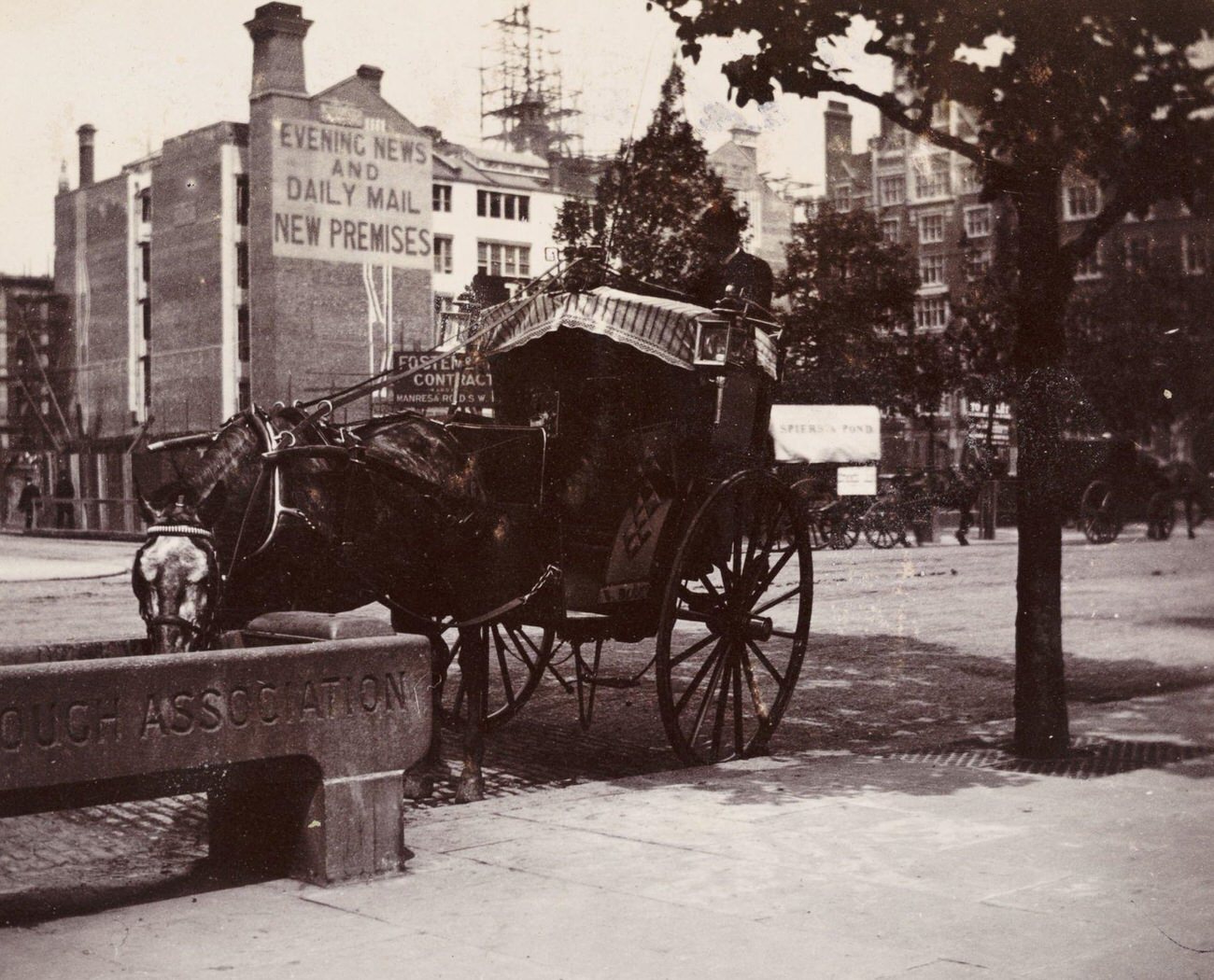A Hansom cab and a horse drinking from a roadside trough in London, circa 1900.