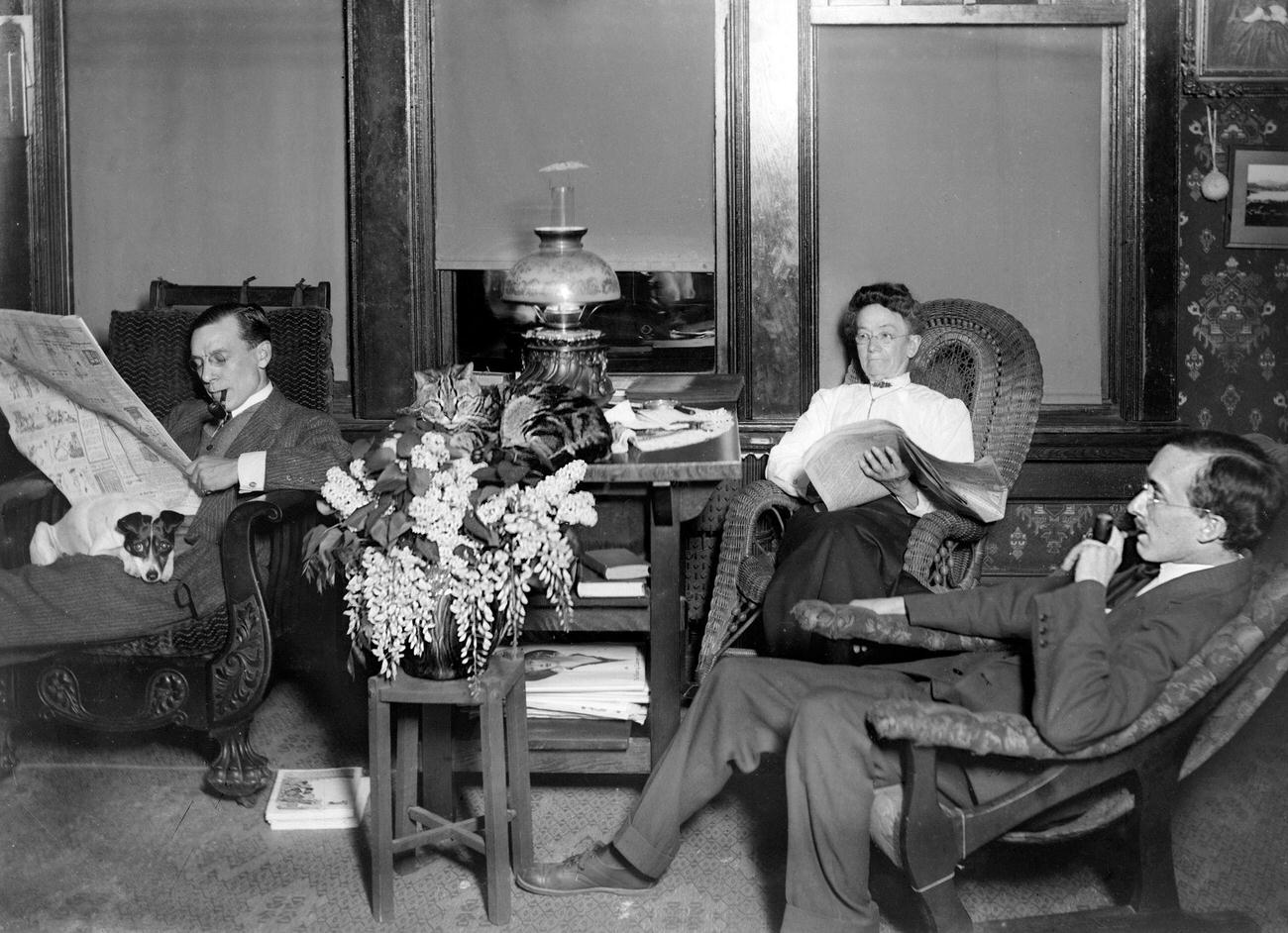 Adults with their pets in a Victorian-era parlor, circa 1900.