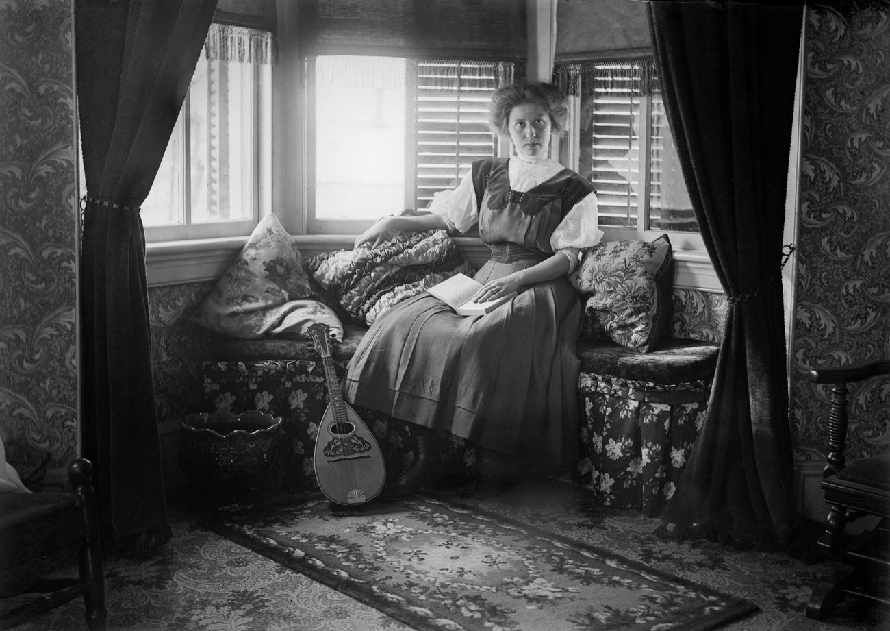 A woman sitting in a Victorian-era parlor, circa 1900.