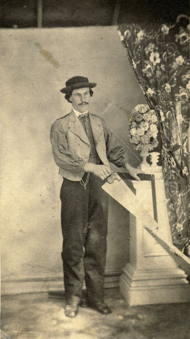 A carpenter stands with his tools of the trade: a saw, steel square and ruler