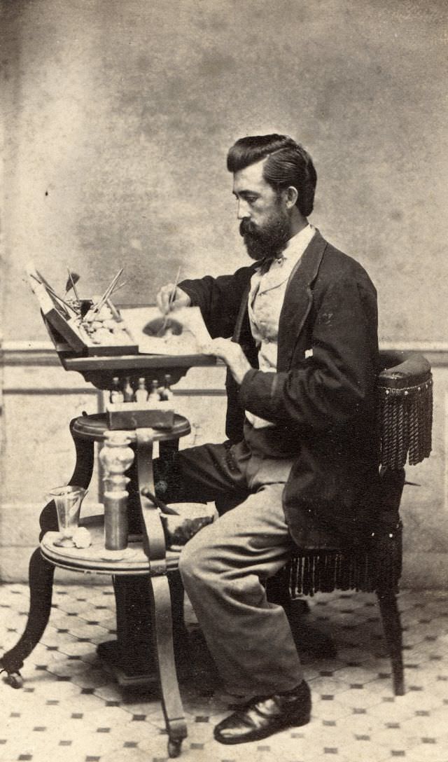 A man poses with the tools of his craft as a colorist, including a box of paints, bottles of dye, brushes and a mortar and pestle