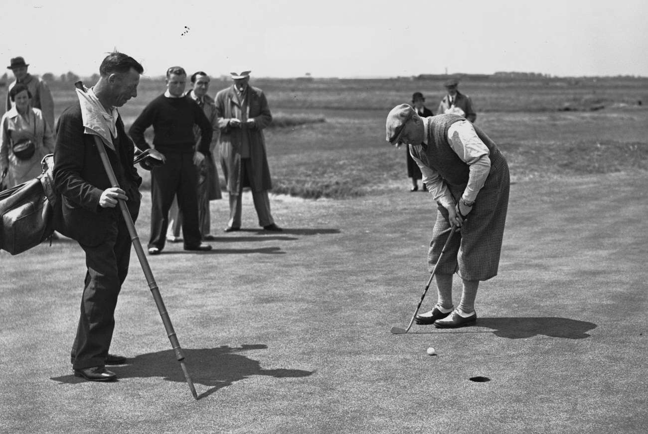 Alfred Perry putting on the green, with spectators.