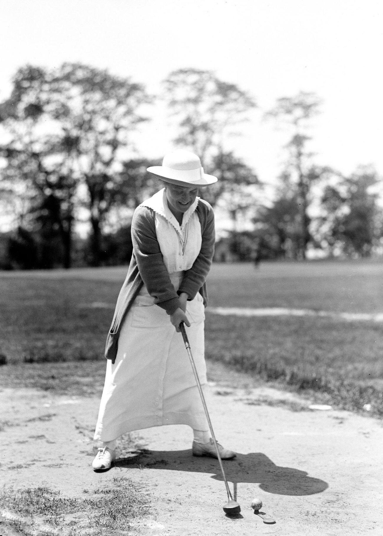 Early 1900s woman hitting golf ball from sand trap, ca. 1913-1917.