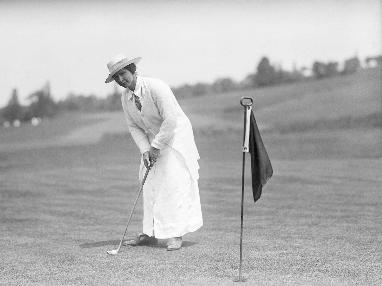 Woman about to swing golf club, 1915.