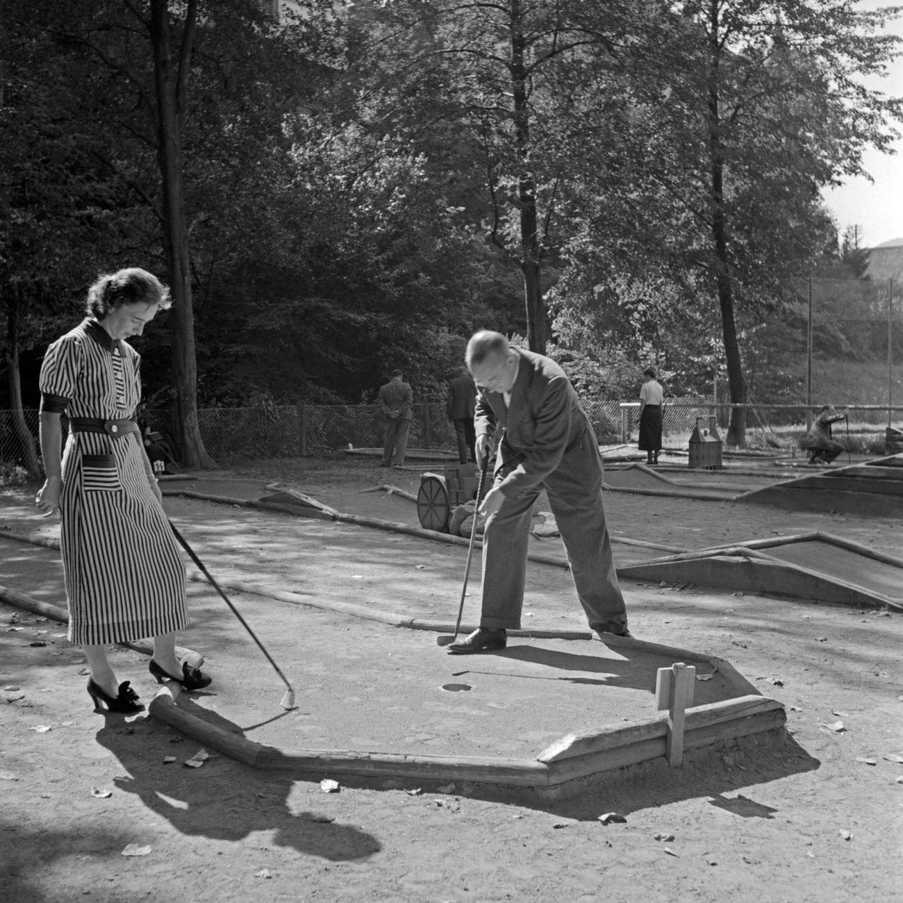 Man and woman playing crazy golf, Herrenalb, Black Forest, Germany, 1930s.