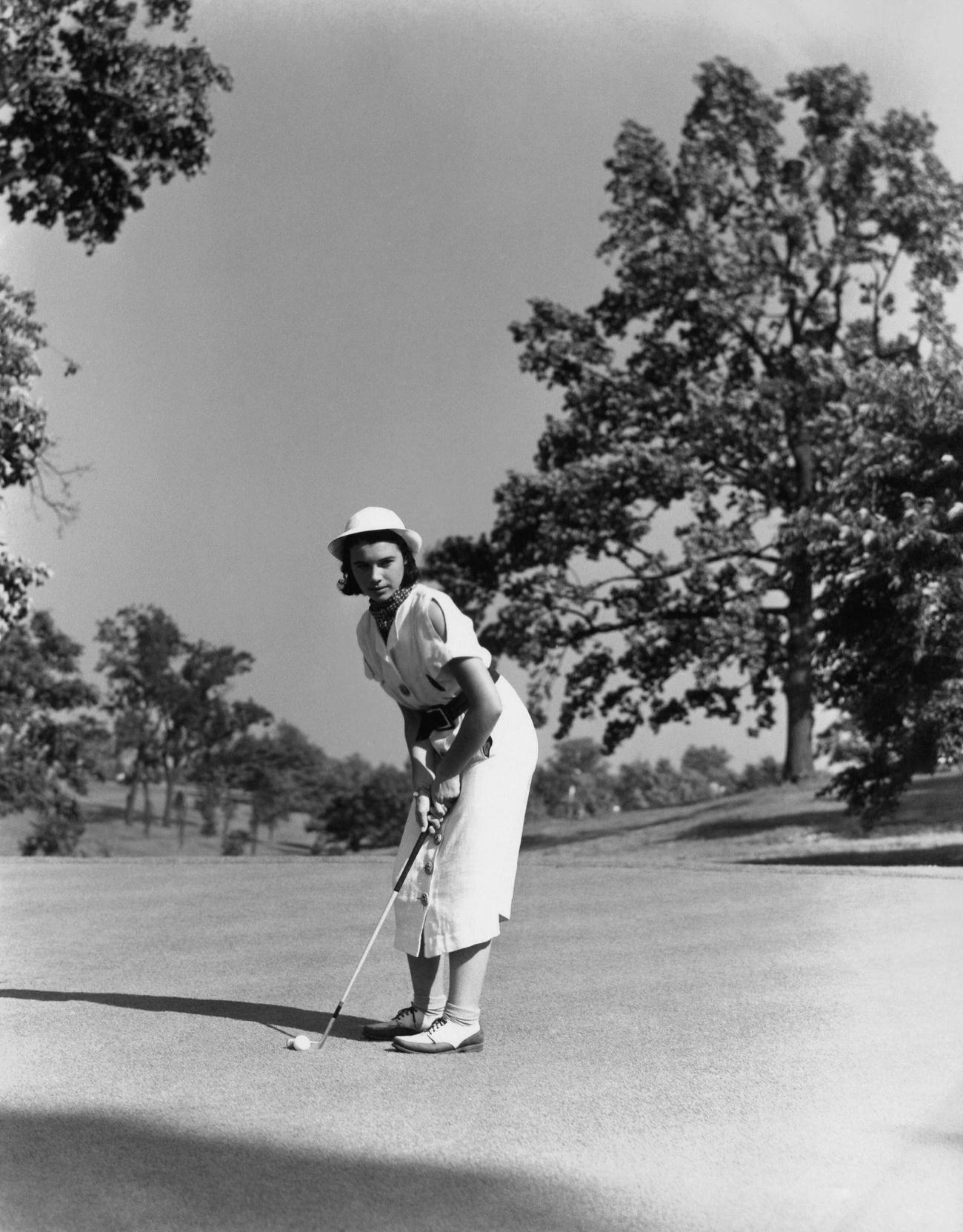 Mid-adult woman playing golf on golf course.