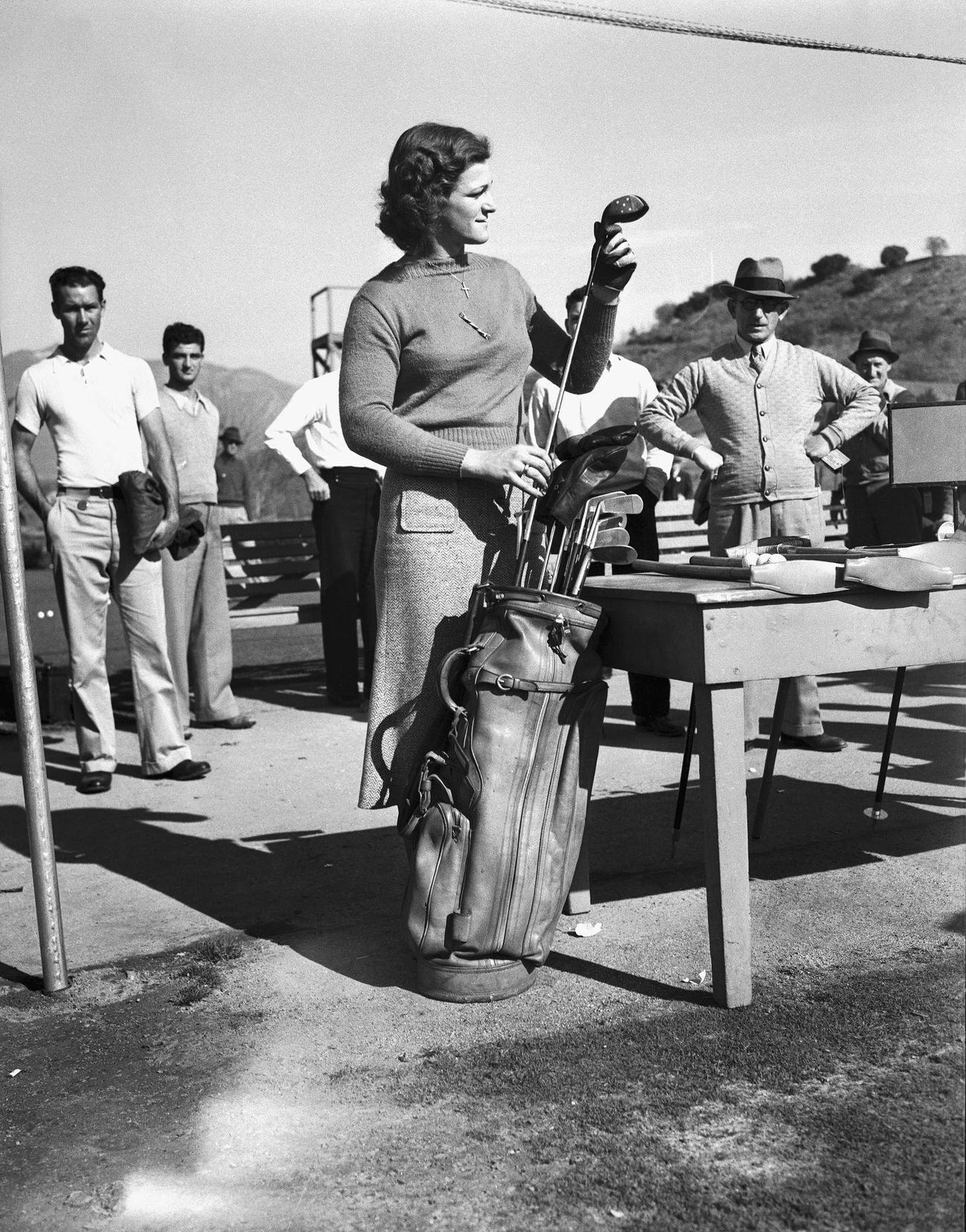 Babe Didrikson examining golf clubs, 13th annual Los Angeles Open Golf Tournament.