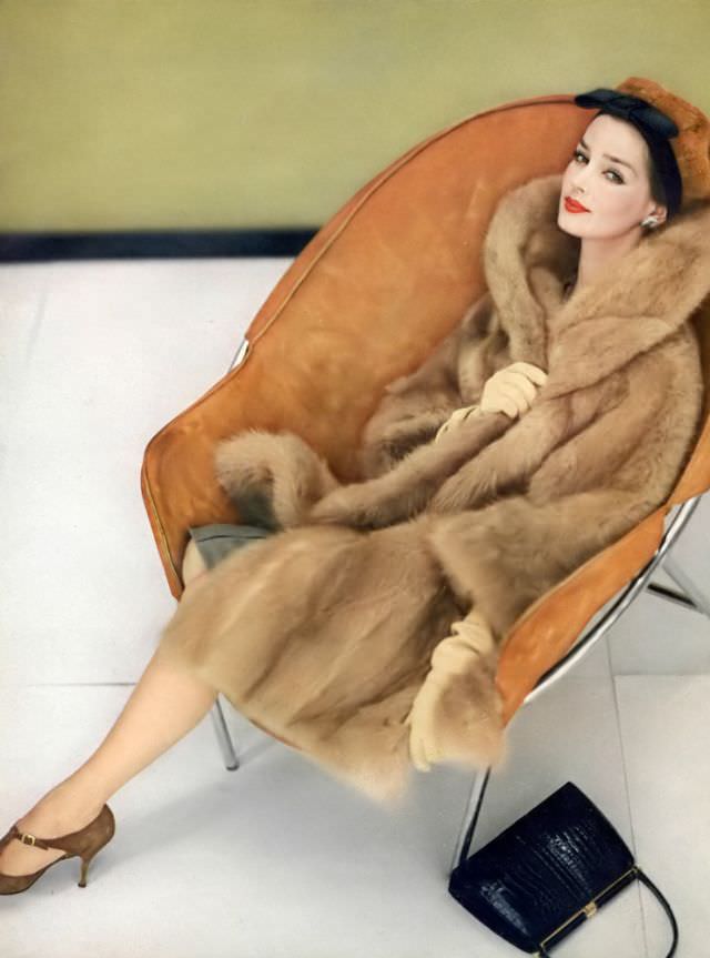 Dolores Hawkins in a cinnamon colored 3/4 length coat of South American guanaco by Georges Kaplan, Vogue, October 15, 1958.