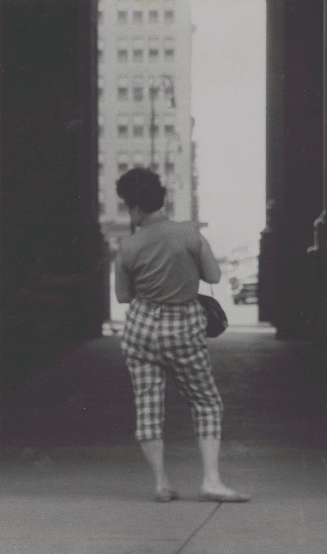 View of woman standing in alleyway, full-length portrait, from behind, June 1957