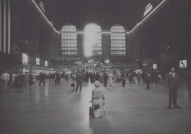 Woman sitting on luggage in Grand Central Terminal, September 1958