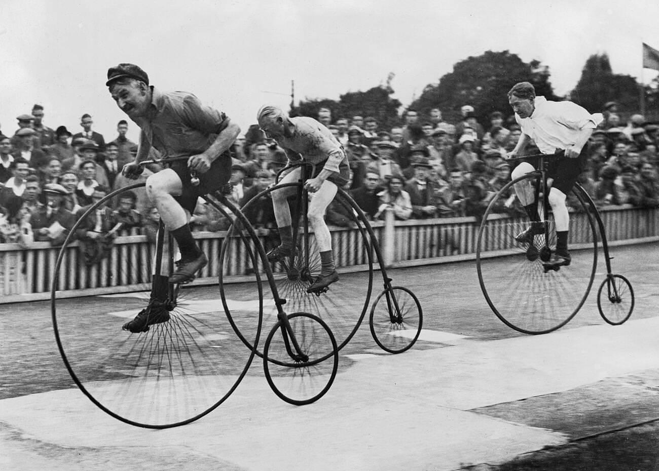 Man riding a penny-farthing bicycle with a woman running beside him, Sweden, 1944.
