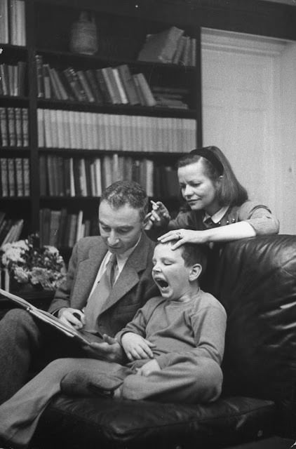 J. Robert Oppenheimer and his wife reading a book to their son, 1949.