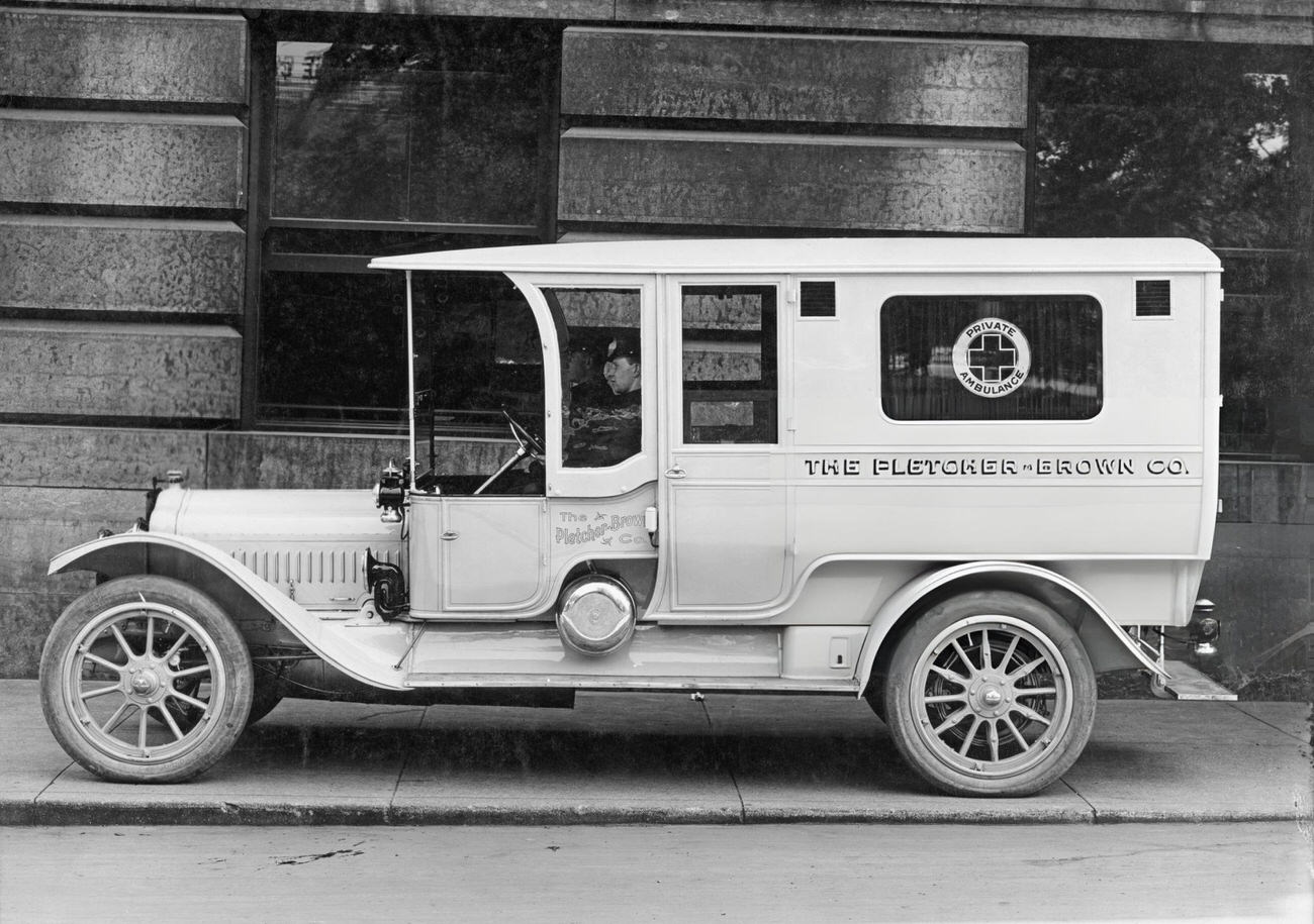 A private ambulance and driver of 'The Fletcher-Brown Company', parked on a sidewalk, Columbus, 1925