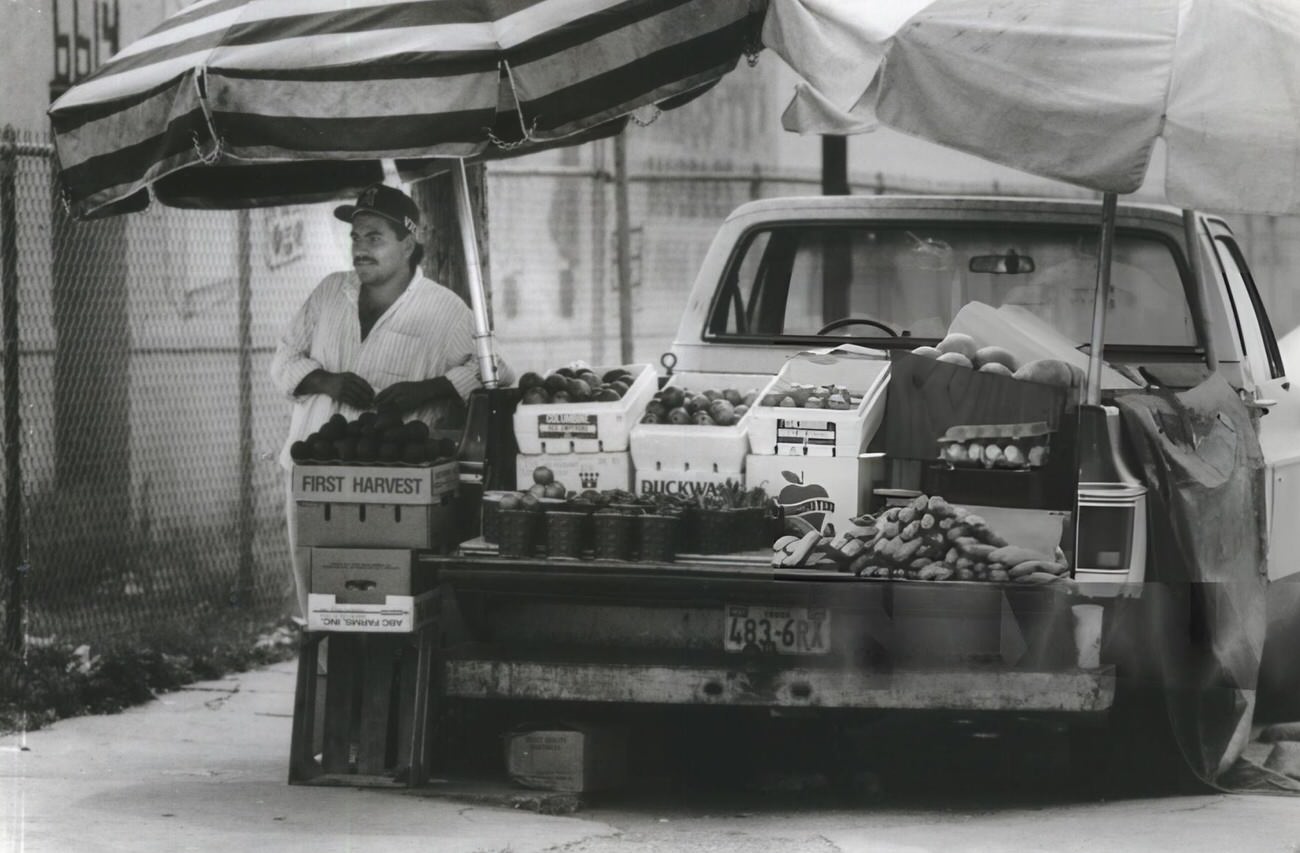 Victor Villejas, 23, from Tampico, Mexico, exemplifies entrepreneurial spirit by selling fruit on Harrisburg, enriching Houston's neighborhood diversity.