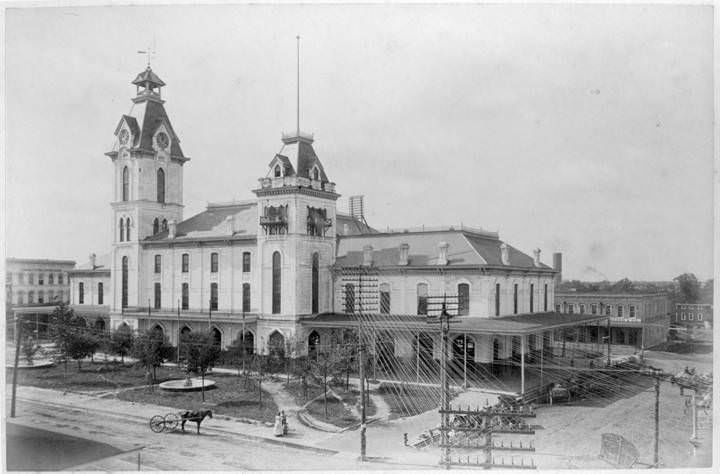 Market House with two towers and horse-drawn vehicles in the street, 1880s