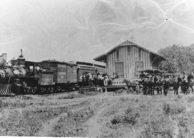 People meeting a train at a depot, 1880s