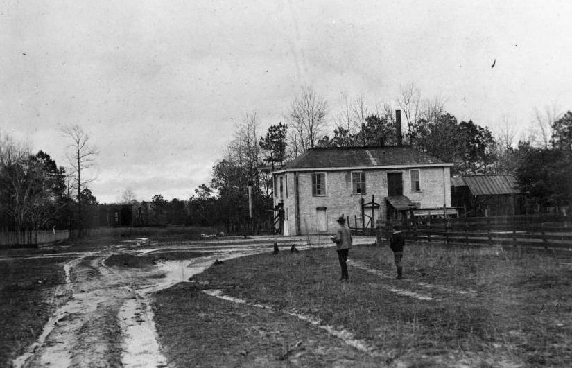 Cotton gin building with a man and boy on a country road, 1896