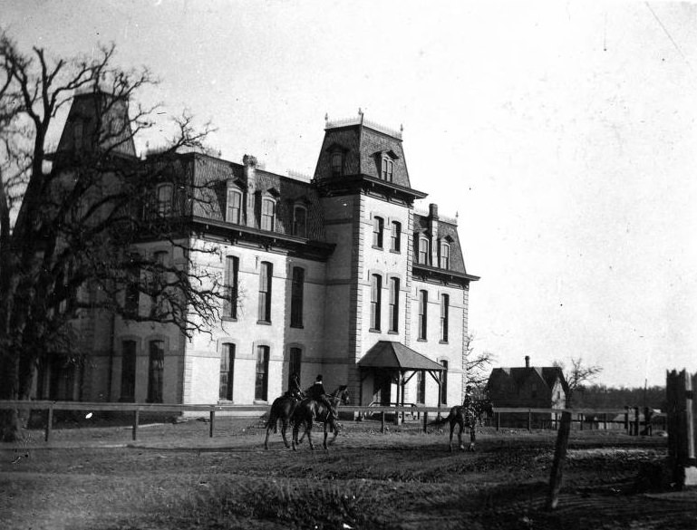 Public school in Denton with horse riders in front, 1896.