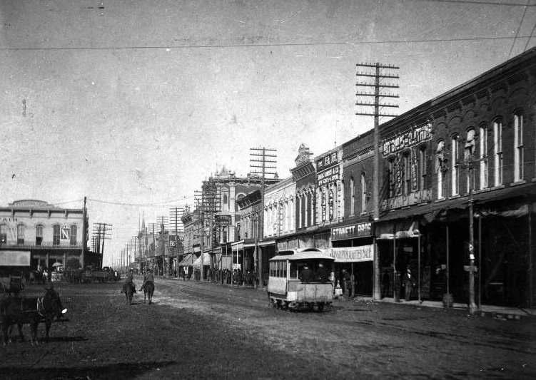 Travis Street in Sherman with storefronts and cable car, 1897