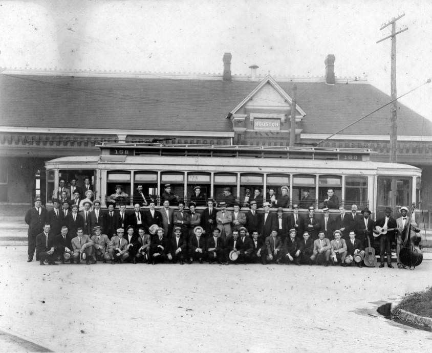 Group of men posing in front of a streetcar, 1910s