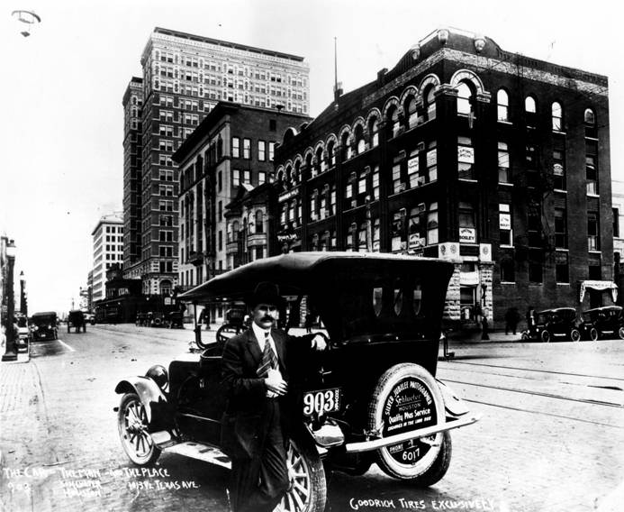 Frank J. Schlueter, photographer, beside automobile, Houston, 1920s