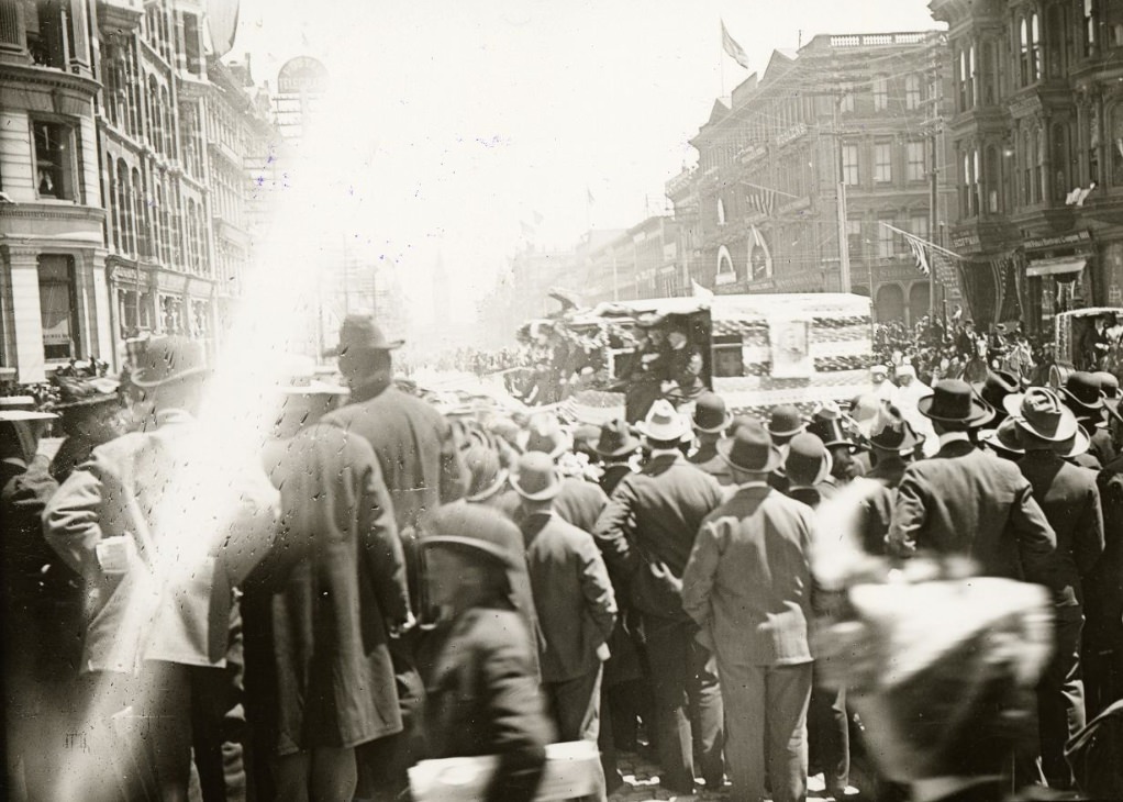 Crowd of people watching a parade on Market Street, east of Montgomery, 1899