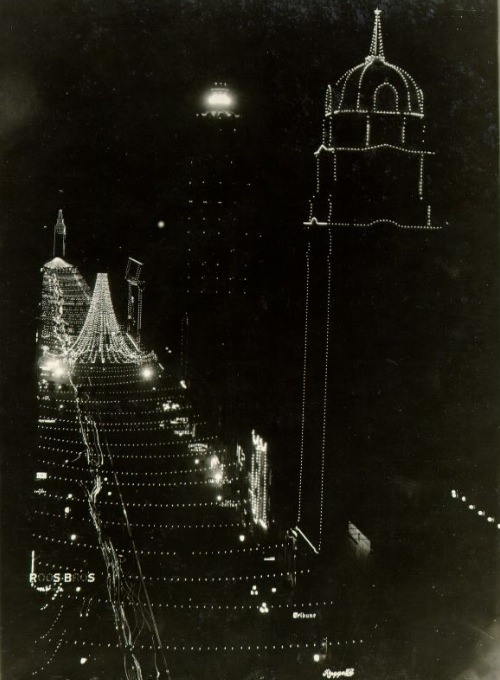 Nighttime view of illuminated decorations on Market Street, looking east from the Phelan Building to the Ferry Building, 1909
