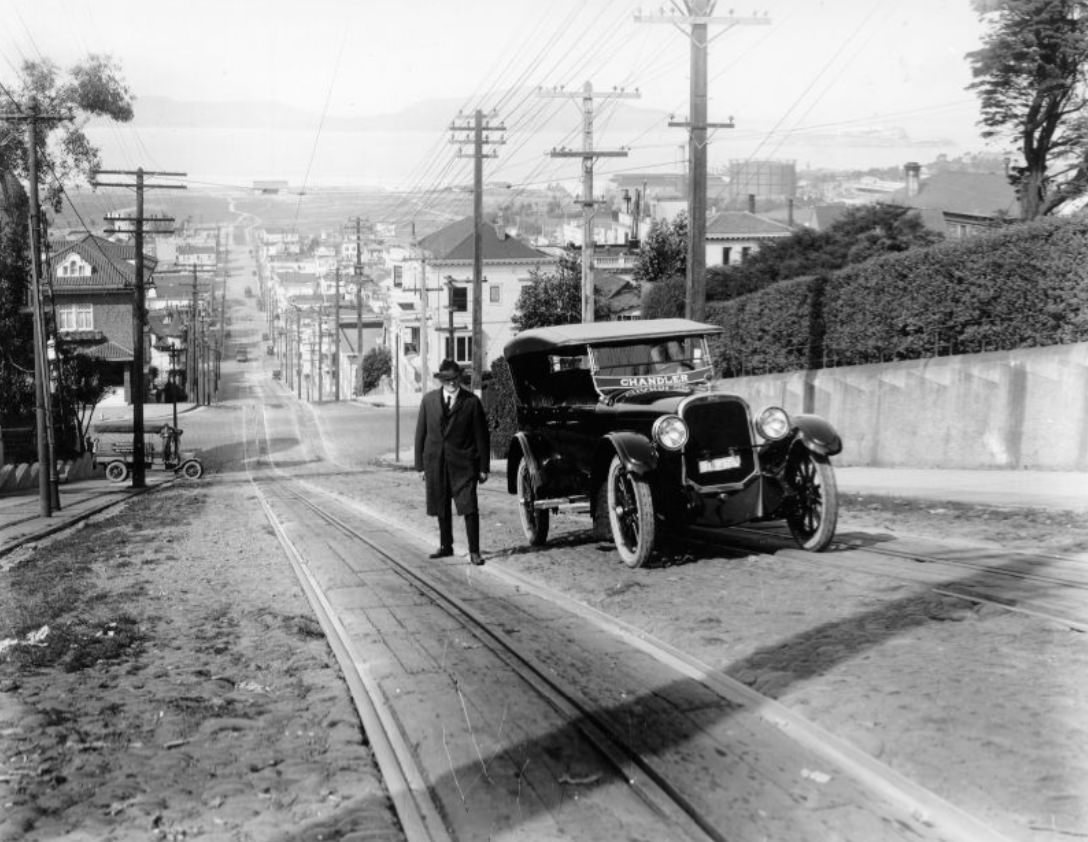 Man next to parked car on Fillmore Street hill, 1922