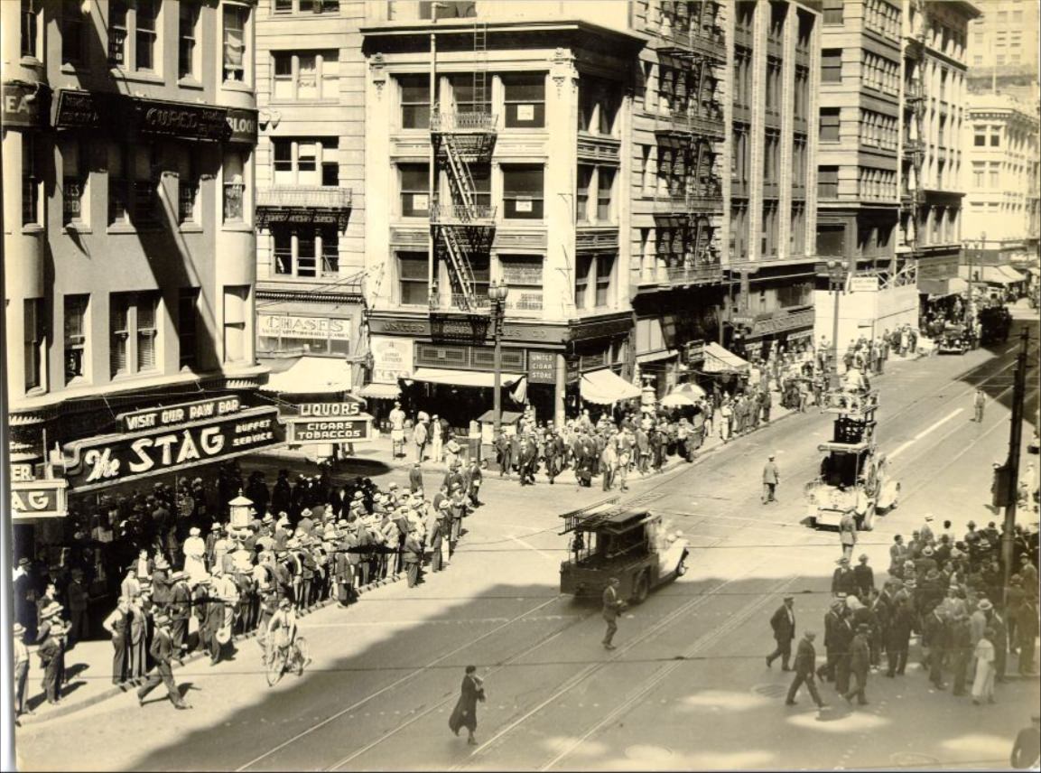 Crowd of people watching workers repair a broken trolley cable on Kearny Street near Market, 1935