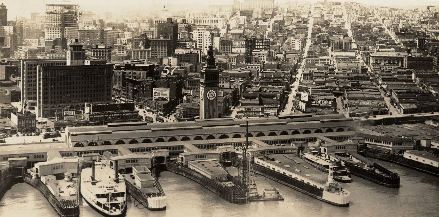 Aerial view from the Bay, looking southwest, of ferry boats, piers, and the Ferry Building, 1930