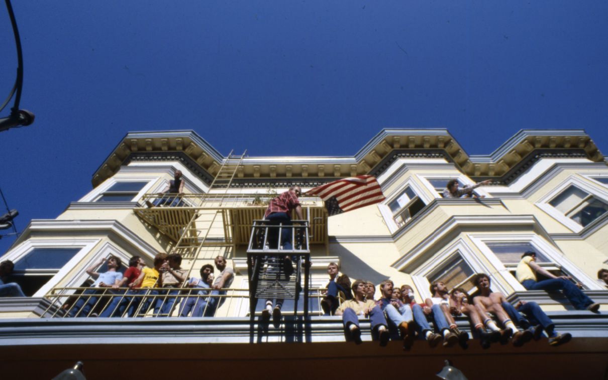 People sitting on fire escapes and a building ledge, 1977.