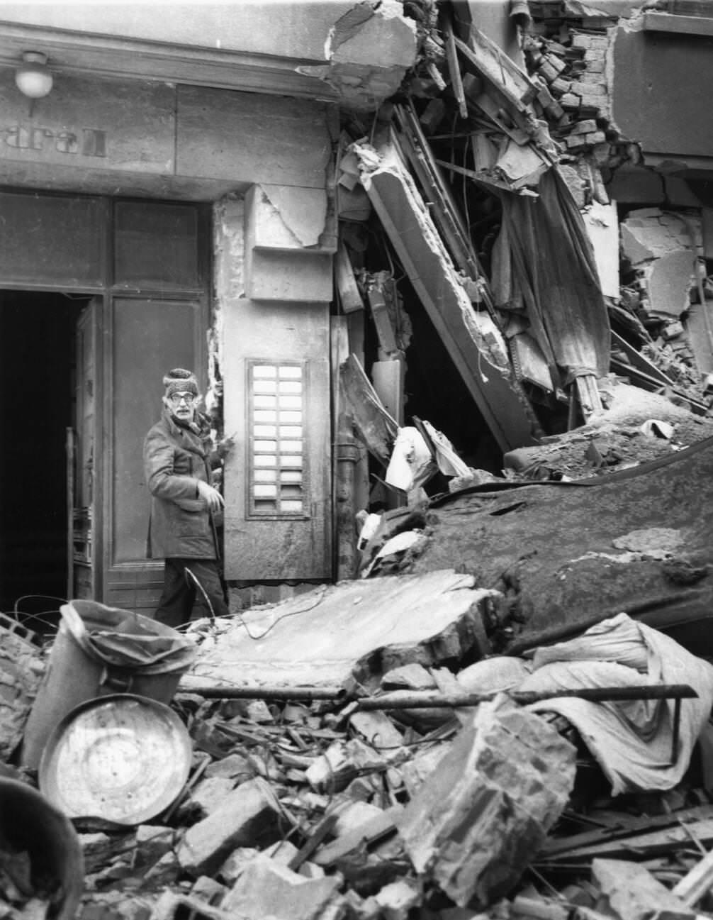 Old man walking through earthquake rubble in Bucharest, Romania, March 1977.