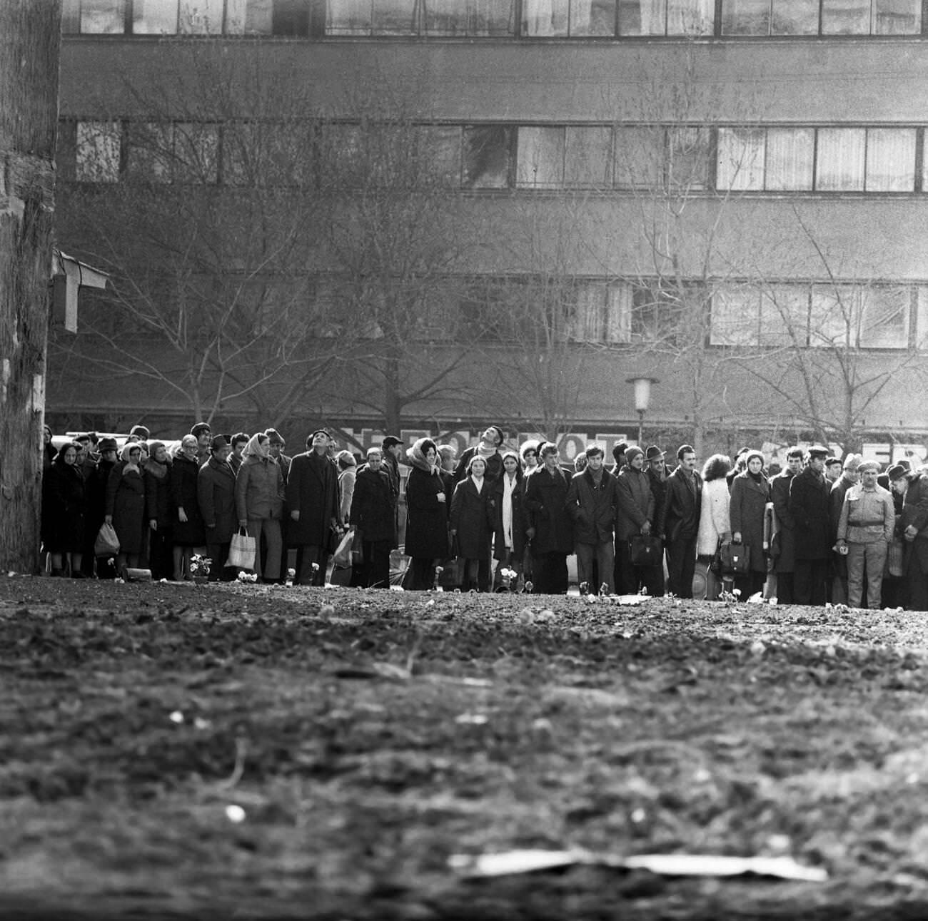 People in line for groceries with flowers for earthquake victims in Bucharest, Romania, March 1977.