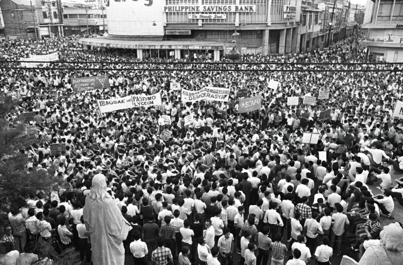 A statue observes 10,000 people protesting governmental activities in Manila, with denouncements of President Ferdinand Marcos.