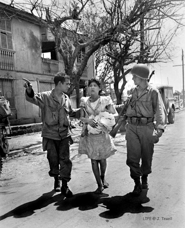 American soldiers helping a Filipino lady to safety and help, Manila, Philippines, February 1945