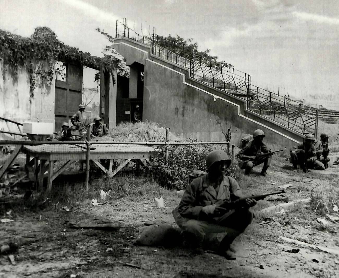 American machine gunners and riflemen defend against Japanese forces from positions at a Manila stadium's back wall, Philippines, 1945.