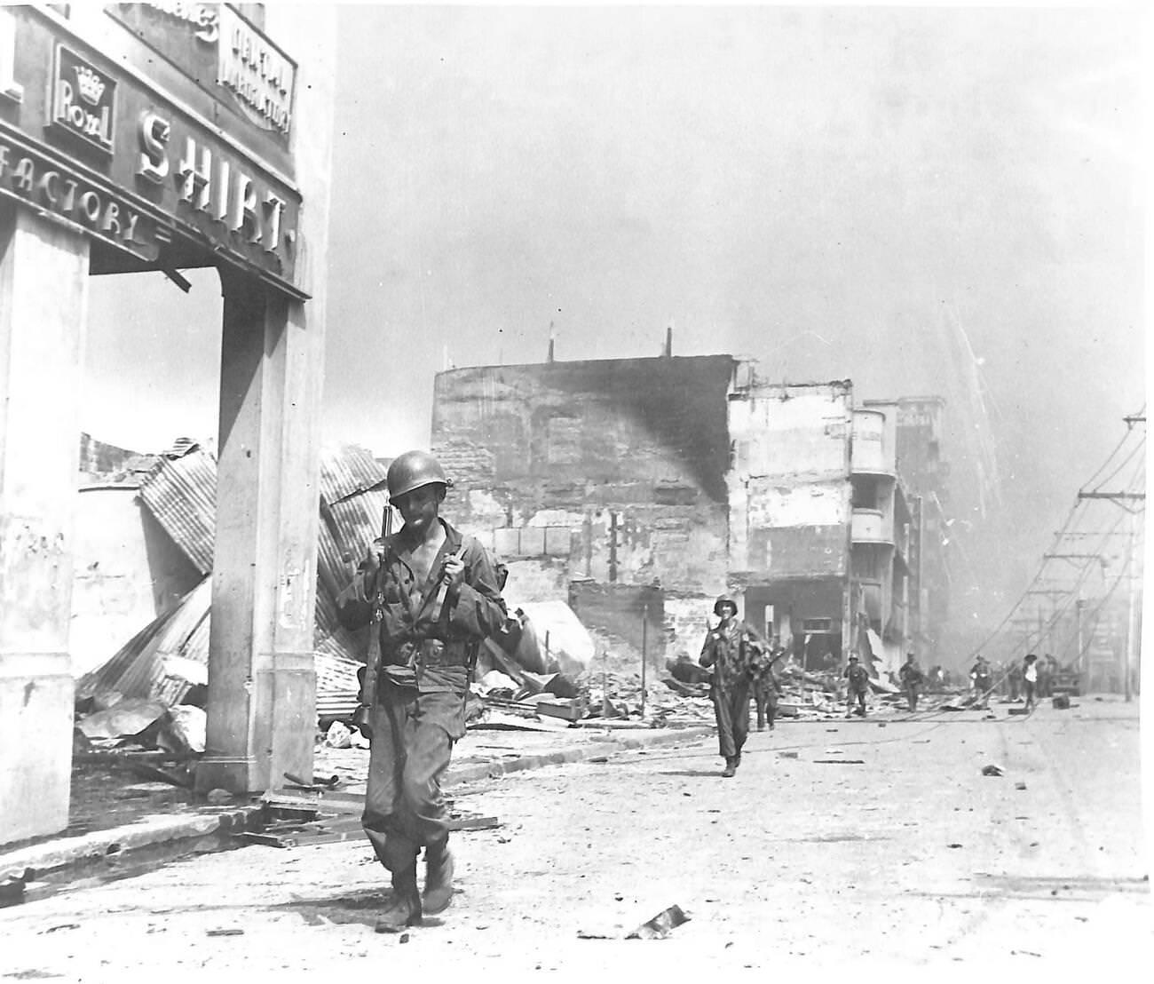 American troops navigate the destroyed business district of Manila en route to the front during the Battle of Manila, 1945.